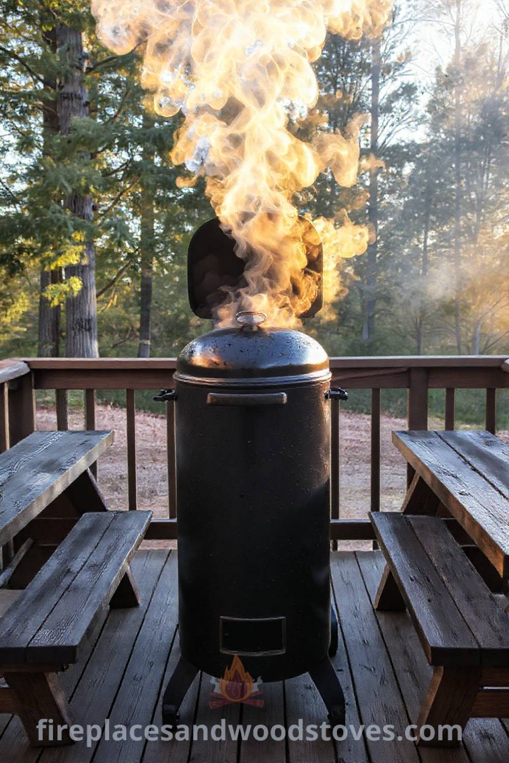Vertical smoker barbecue on a wooden deck with weathered benches, surrounded by trees, creating a cozy outdoor setting perfect for gatherings, sunny afternoons, and delicious grilled feasts. Visit patioandhomefurniture.com for incredible ideas that will wow your guests.