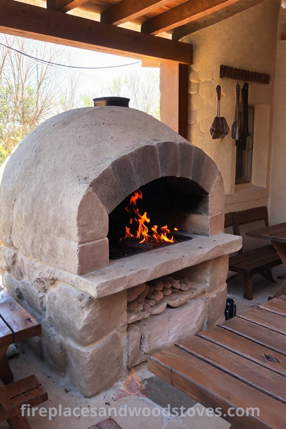 Stone BBQ oven on a sunlit patio, with flickering flames and rustic wooden tables, creating a warm and inviting outdoor atmosphere perfect for gatherings. Visit patioandhomefurniture.com for incredible ideas that will wow your guests.