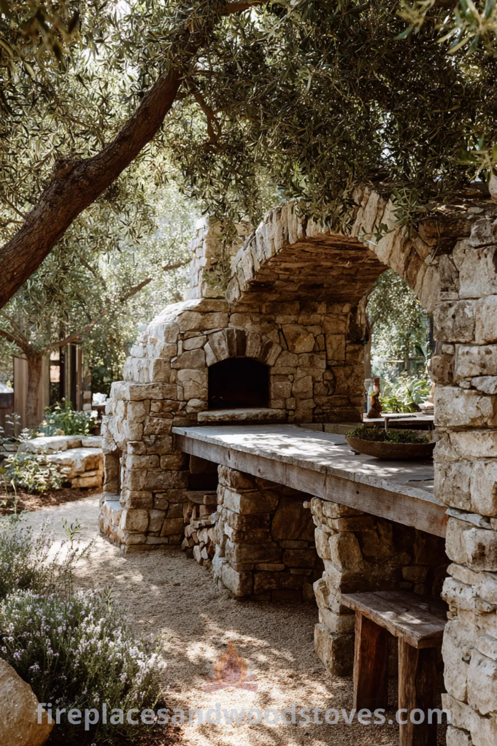 Outdoor area featuring a rustic stone fireplace with a built-in pizza oven, olive trees nearby, and warm mediterranean fireplace vibes.