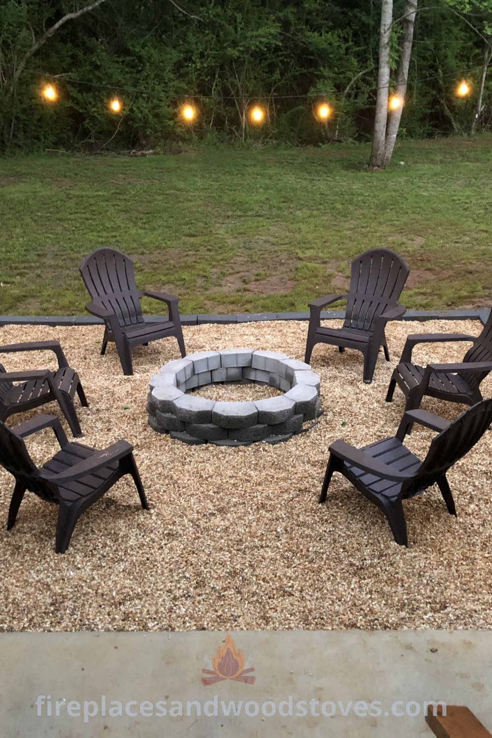 A cozy backyard scene featuring a wood-burning fire pit surrounded by lawn chairs and string lights, enhancing outdoor relaxation with stylish fire pit ideas for landscaping. Discover more design inspiration at patioandhomefurniture.com.