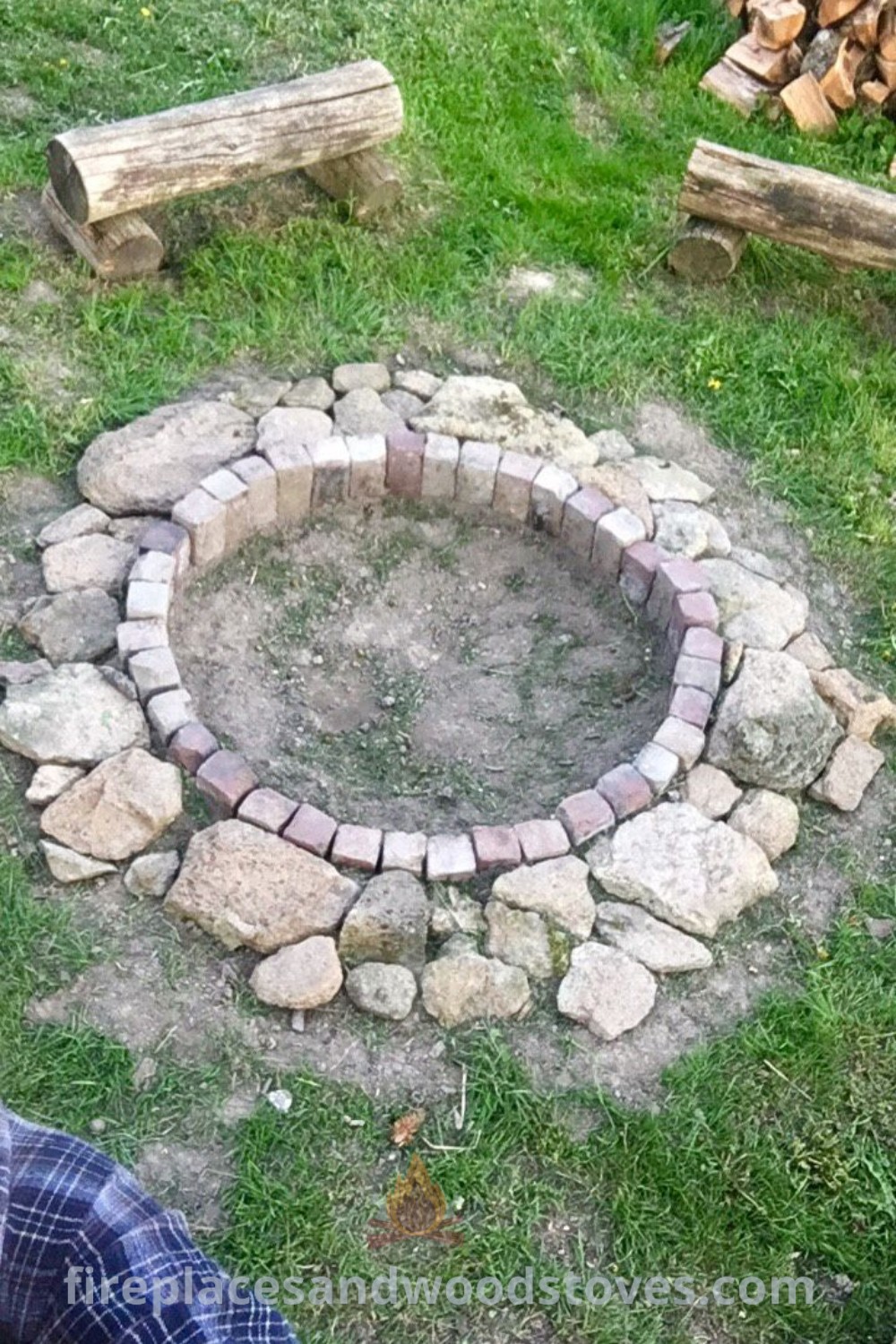 A natural fire pit in a field, surrounded by logs and lush grass, creating a cozy outdoor fire pit area perfect for gatherings. Discover stylish designs and inspiring ideas for your backyard at patioandhomefurniture.com.