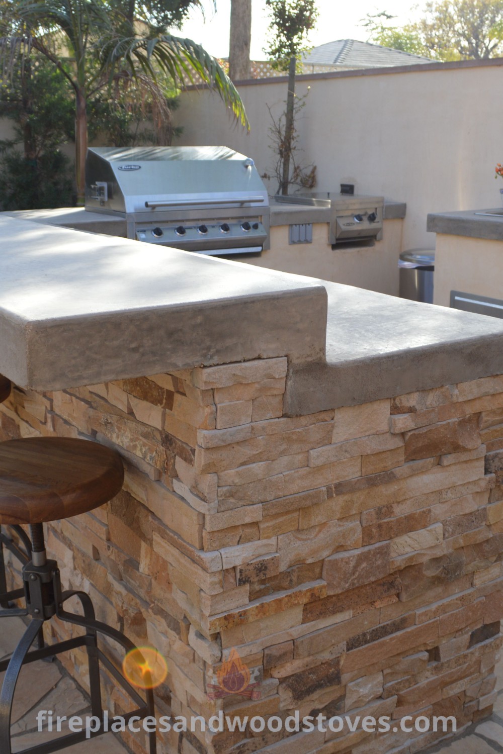 An outdoor kitchen with bar stools and grill, featuring stylish outdoor kitchen cabinets and a cozy BBQ bar for backyard dining. Discover incredible designs transforming your outdoor space at patioandhomefurniture.com.