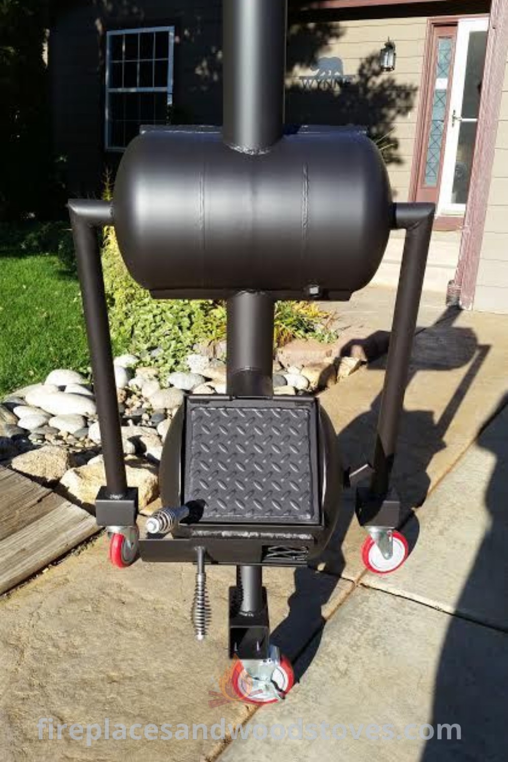 An outdoor grill with wheels positioned on a grassy area in front of a house, showcasing stylish designs that transform your backyard for memorable BBQ gatherings. Explore innovative smoker ideas and enhance your outdoor experience at patioandhomefurniture.com.