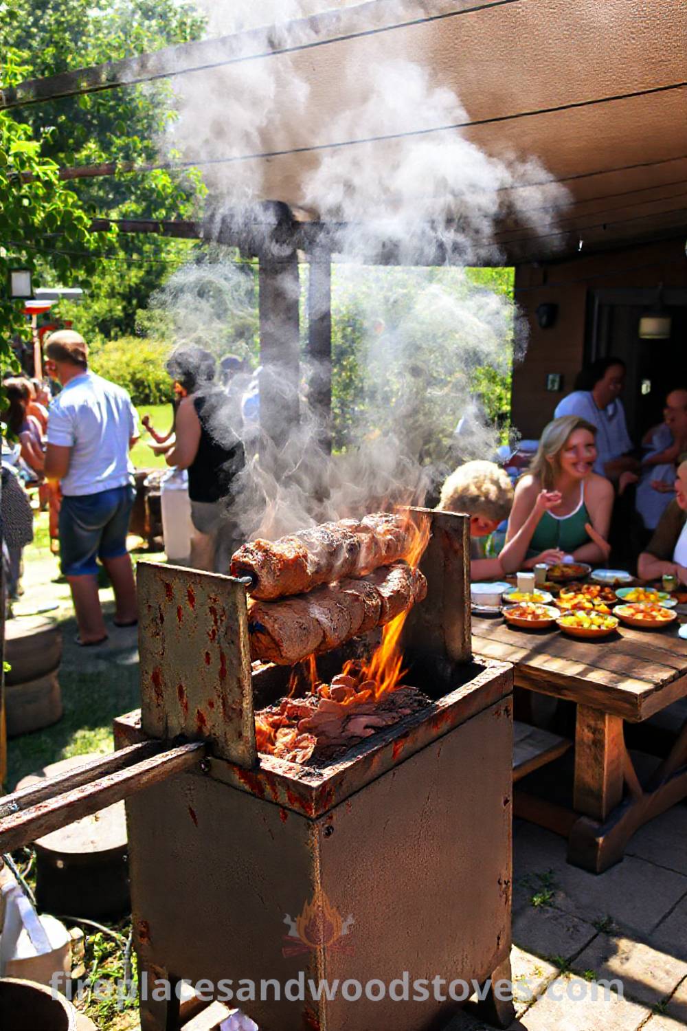 Sturdy spit BBQ in a sunlit patio corner, with rustic wooden tables and colorful dishes, creating a cozy atmosphere for gatherings. Visit patioandhomefurniture.com for incredible outdoor design ideas that will wow your guests.
