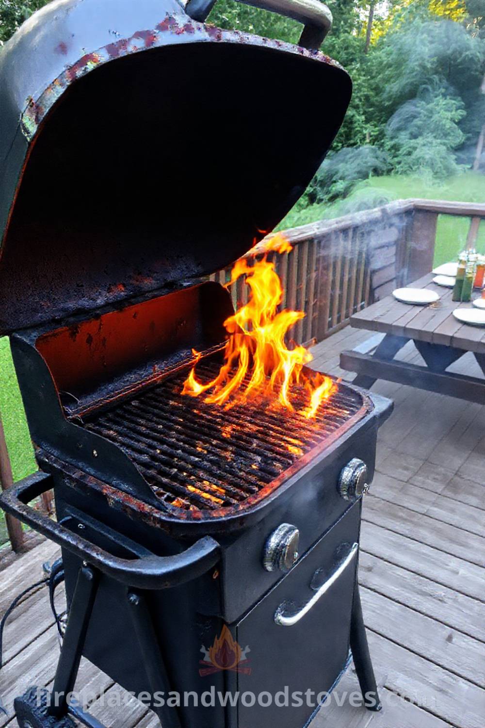 Sturdy outdoor BBQ grill on a wooden deck with flames leaping from the grates, surrounded by greenery and a picnic table ready for summer gatherings. Visit patioandhomefurniture.com for stylish outdoor design ideas that will wow your guests.