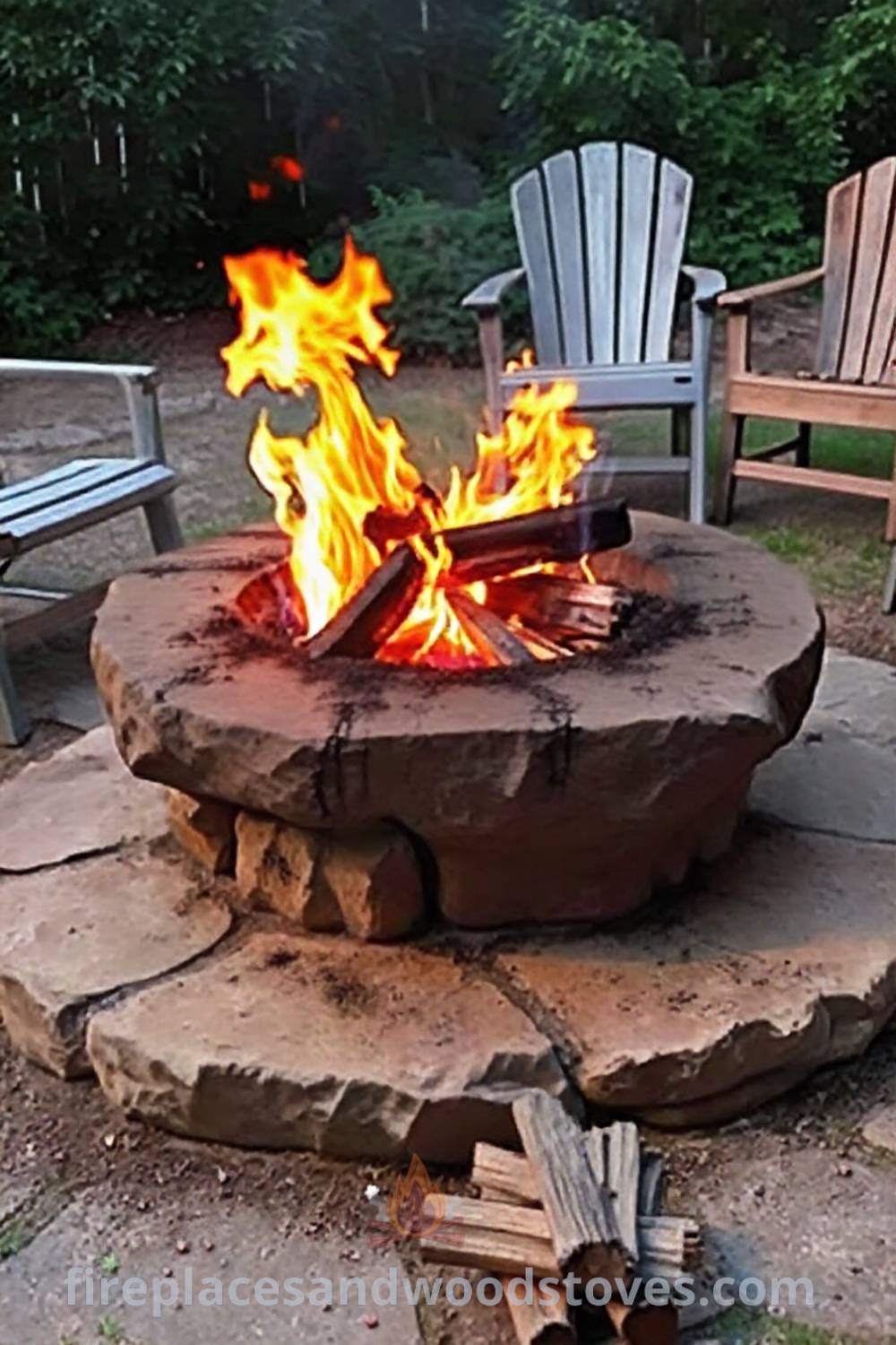 Cozy wood-burning fire pit on a stone base surrounded by mismatched chairs, glowing flames illuminating the greenery, creating a warm and inviting atmosphere for gatherings. Visit patioandhomefurniture.com for incredible ideas that will wow your guests in your outdoor space.