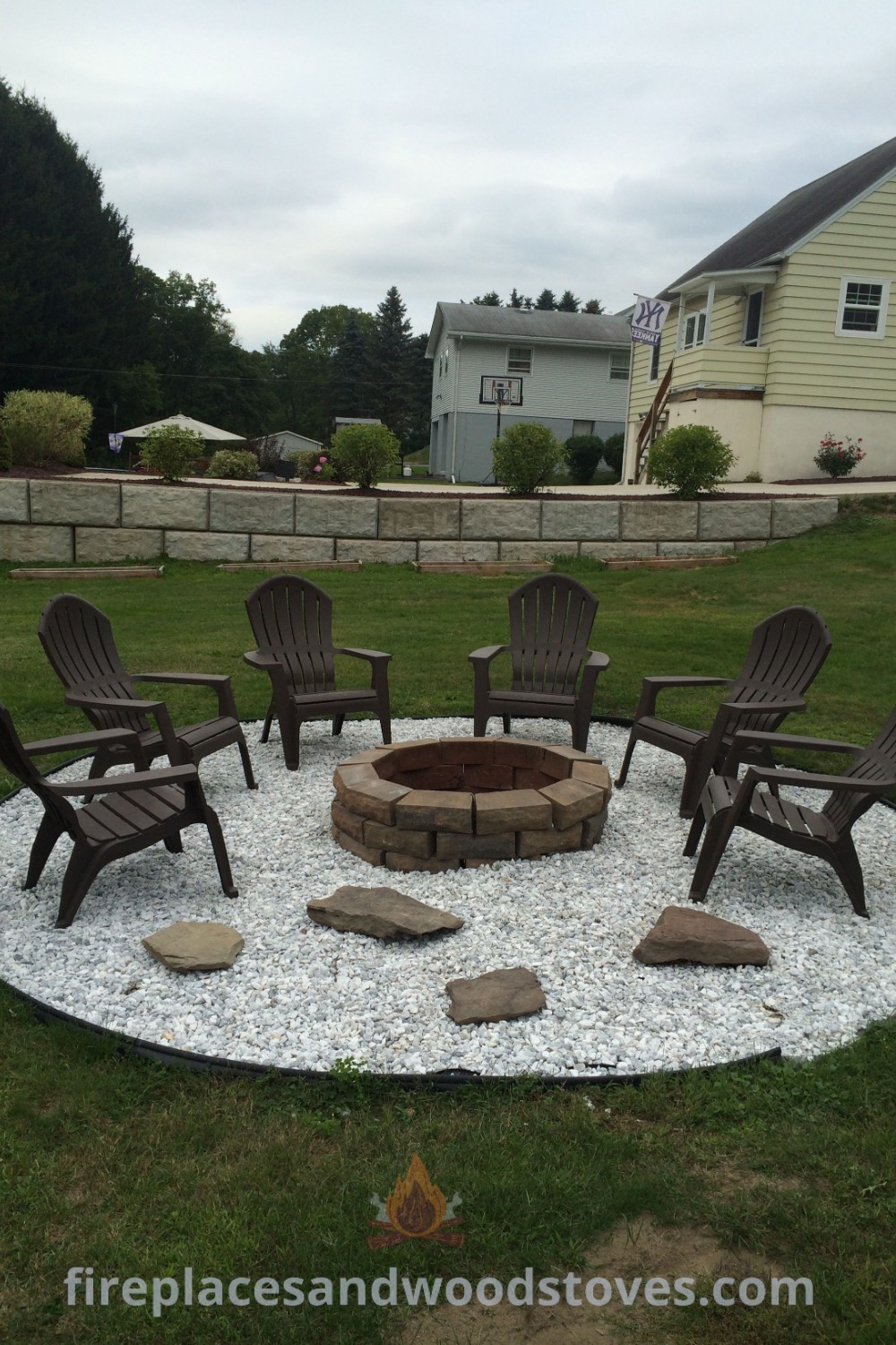 A cozy fire pit surrounded by chairs on a pea gravel patio with grass and rocks, creating a stylish outdoor space. Discover amazing outdoor fire pit designs and gravel patio ideas at patioandhomefurniture.com.