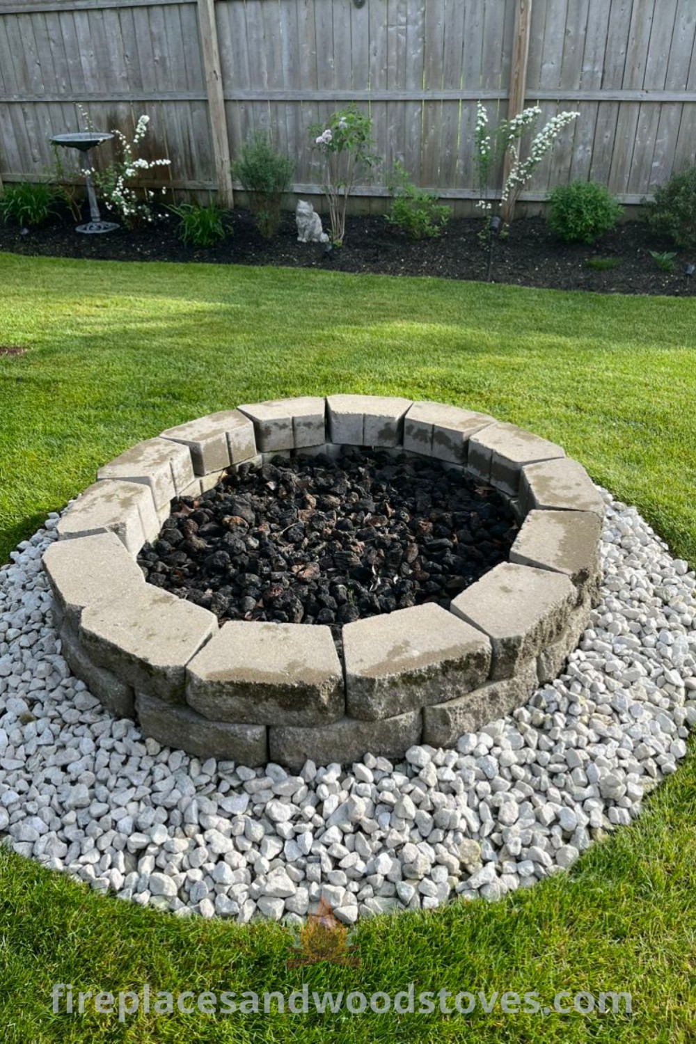A stone fire pit on a lush green field, featuring stylish designs for creating a cozy outdoor area. Ideas include rectangle and simple layouts, perfect for budget-friendly backyard transformations. Explore more amazing outdoor fire pit ideas at patioandhomefurniture.com.
