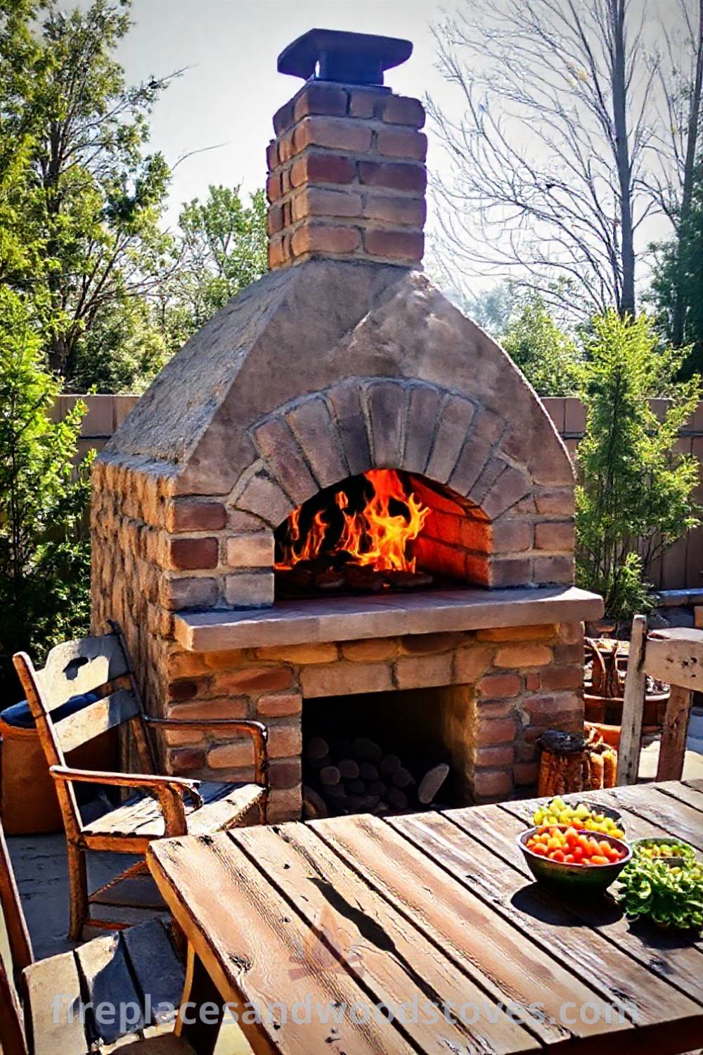 Sturdy stone BBQ oven on a sunlit patio with flames and a colorful spread of sides, surrounded by mismatched chairs creating a cozy outdoor gathering space. Visit patioandhomefurniture.com for stylish ideas that will wow your guests.