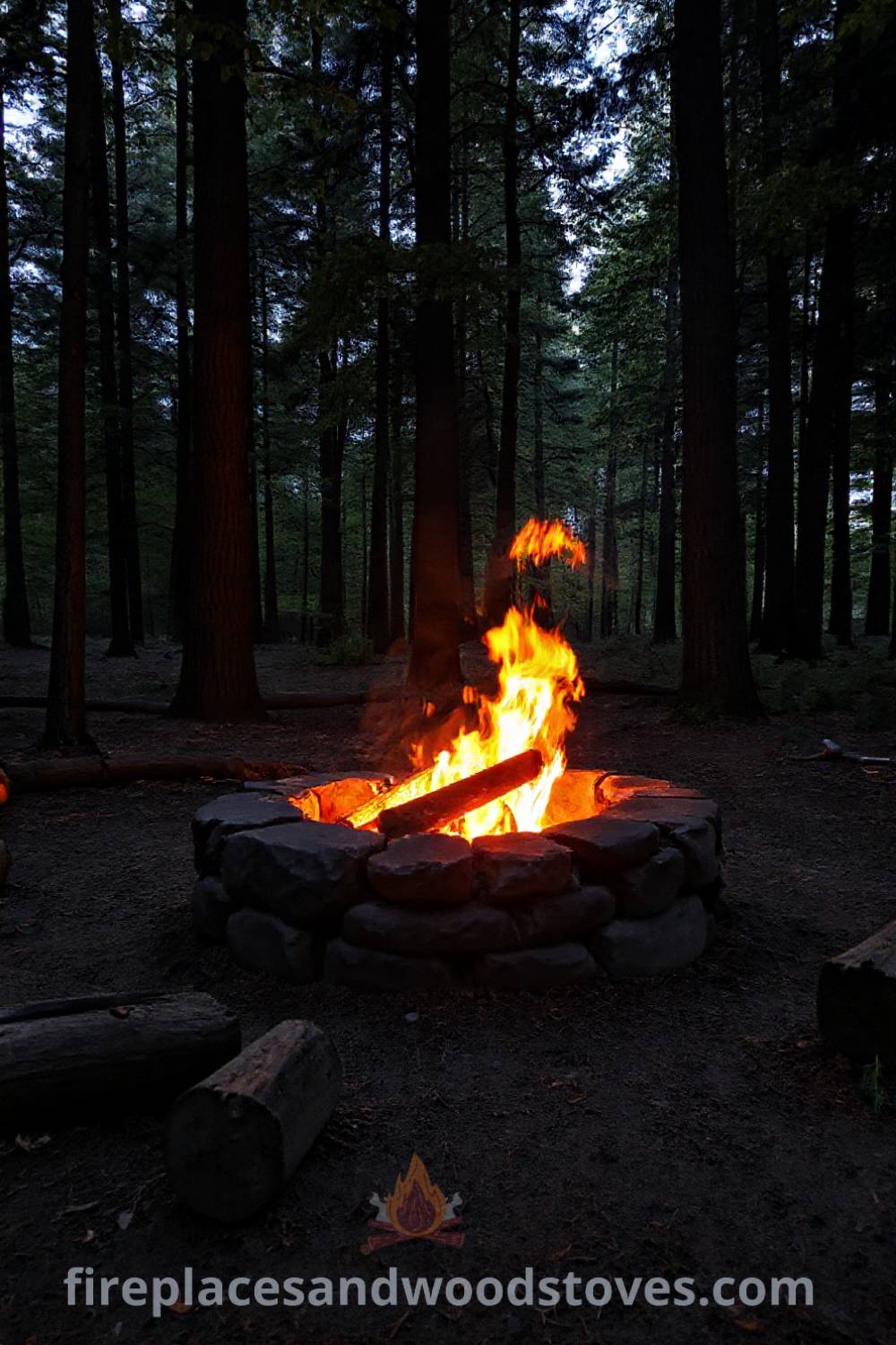 Stone camping fire pit in a forest clearing with flickering flames and logs arranged for seating, creating a cozy atmosphere for outdoor gatherings, perfect for storytelling under the stars. Visit patioandhomefurniture.com for stylish outdoor design ideas.