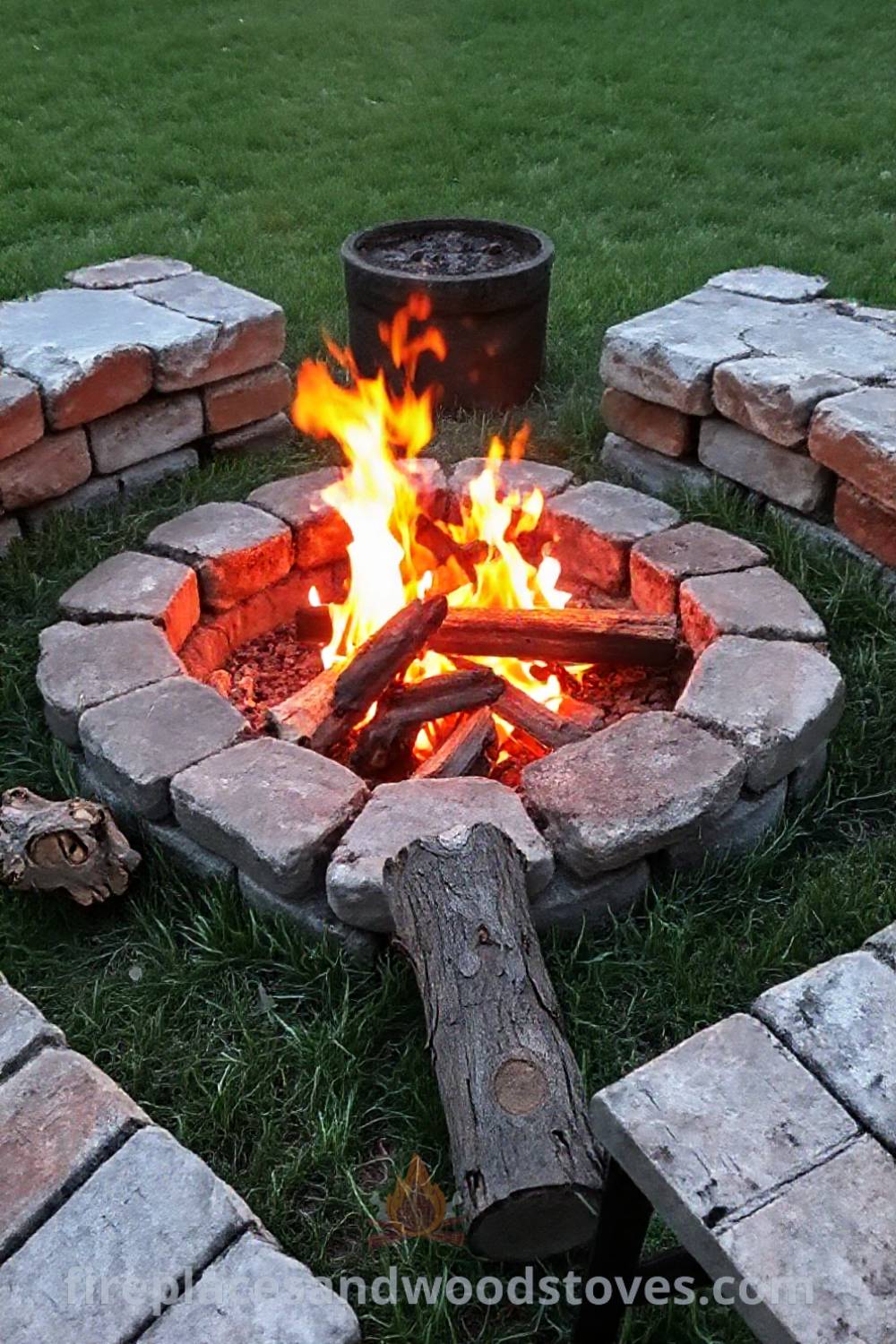 Stone fire pit nestled in a cozy alcove of grass, surrounded by mismatched seats and logs, creating a warm outdoor gathering space filled with inviting flames. Visit patioandhomefurniture.com for stylish backyard design ideas that will wow your guests.