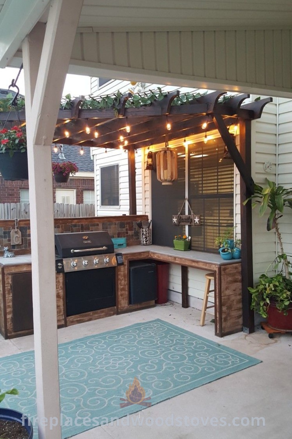 An outdoor kitchen featuring lights and potted plants under a pergolated roof, designed for backyard grilling with a stylish and cozy atmosphere. Discover these outdoor kitchen design ideas at patioandhomefurniture.com.