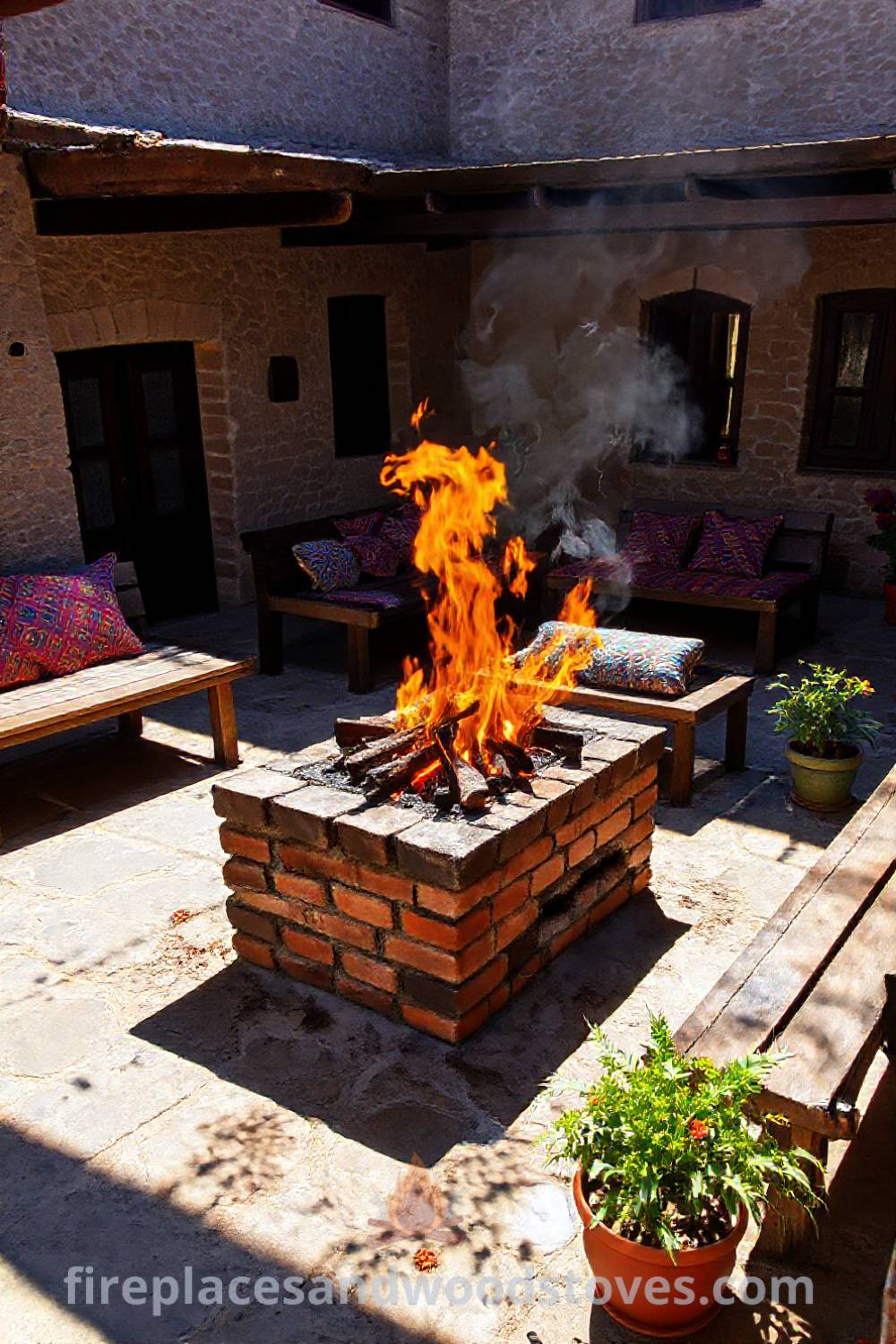 Turkish mangal barbecue in a sun-dappled courtyard with bright orange flames, colorful cushions, and potted plants creating a cozy outdoor atmosphere, perfect for gatherings. Visit patioandhomefurniture.com for stylish outdoor design ideas that will wow your guests.