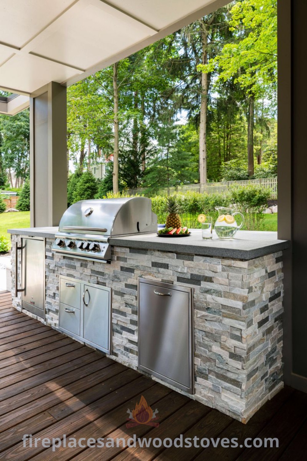 An outdoor kitchen with a grill, sink, and countertop on a deck in front of trees, showcasing stylish designs transforming the backyard. Explore outdoor kitchen ideas for functional and aesthetic enhancement at patioandhomefurniture.com.