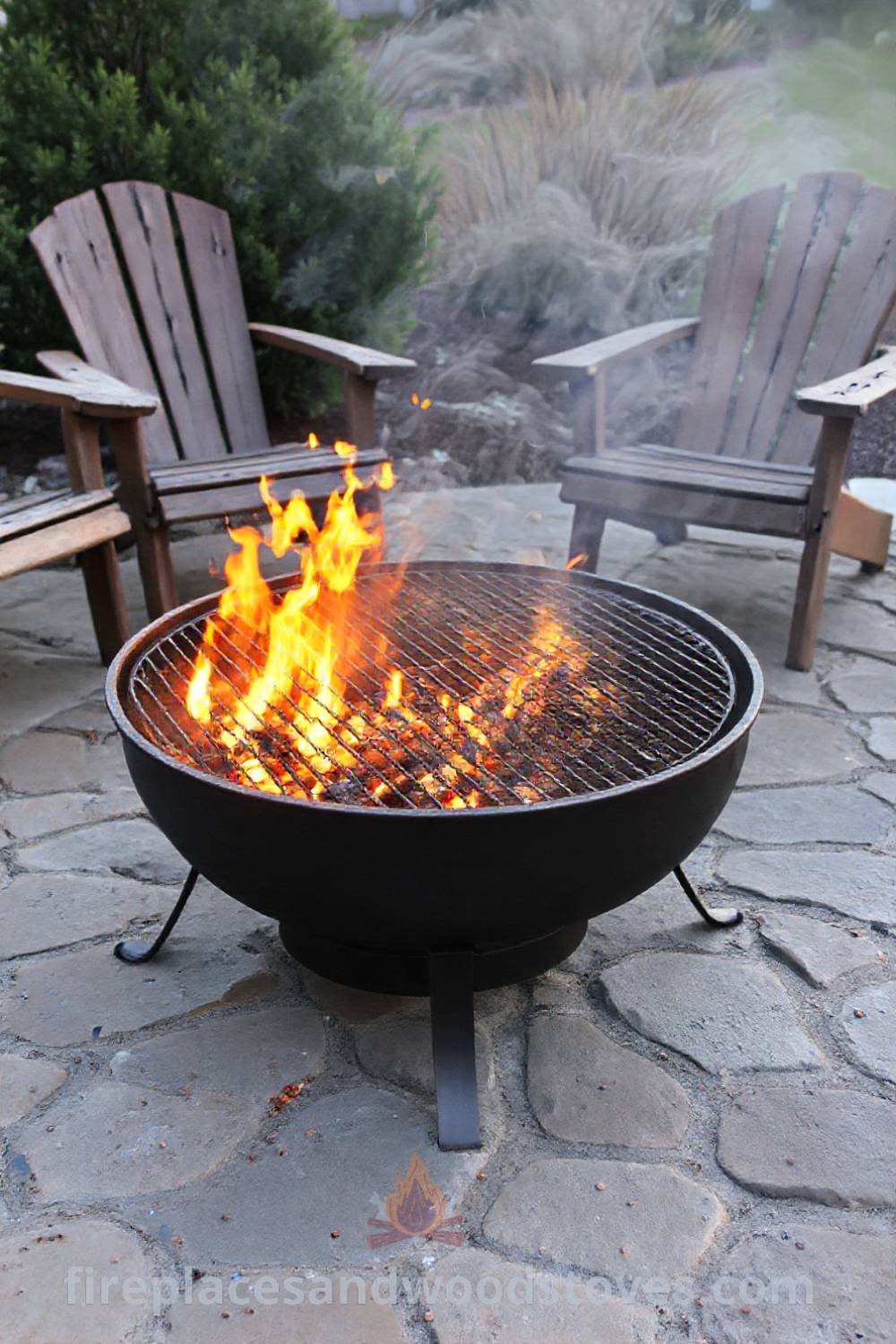 Charcoal-burning metal fire pit on a stone patio, surrounded by wooden chairs, creating a cozy atmosphere for gatherings and evening conversations. Visit patioandhomefurniture.com for stylish outdoor design ideas that will wow your guests.