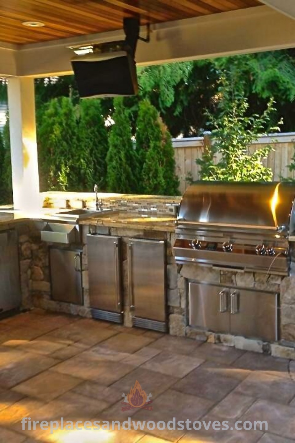 An outdoor kitchen with grill, sink, and television, showcasing stylish outdoor kitchen countertops and bars, ideal for creating an amazing backyard space. Discover incredible ideas for transforming your patio at patioandhomefurniture.com.