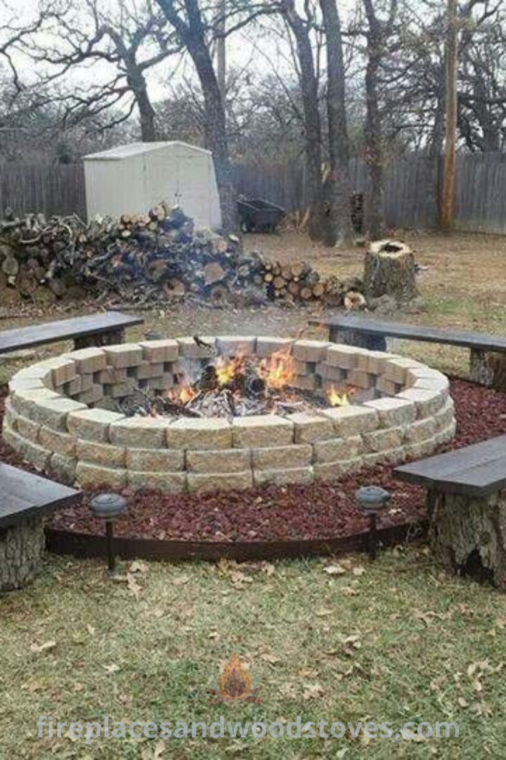 A cozy fire pit made with cinder blocks and surrounded by benches, set in a grassy area with trees, ideal for outdoor gatherings. Discover creative and stylish backyard designs to wow your guests at patioandhomefurniture.com.