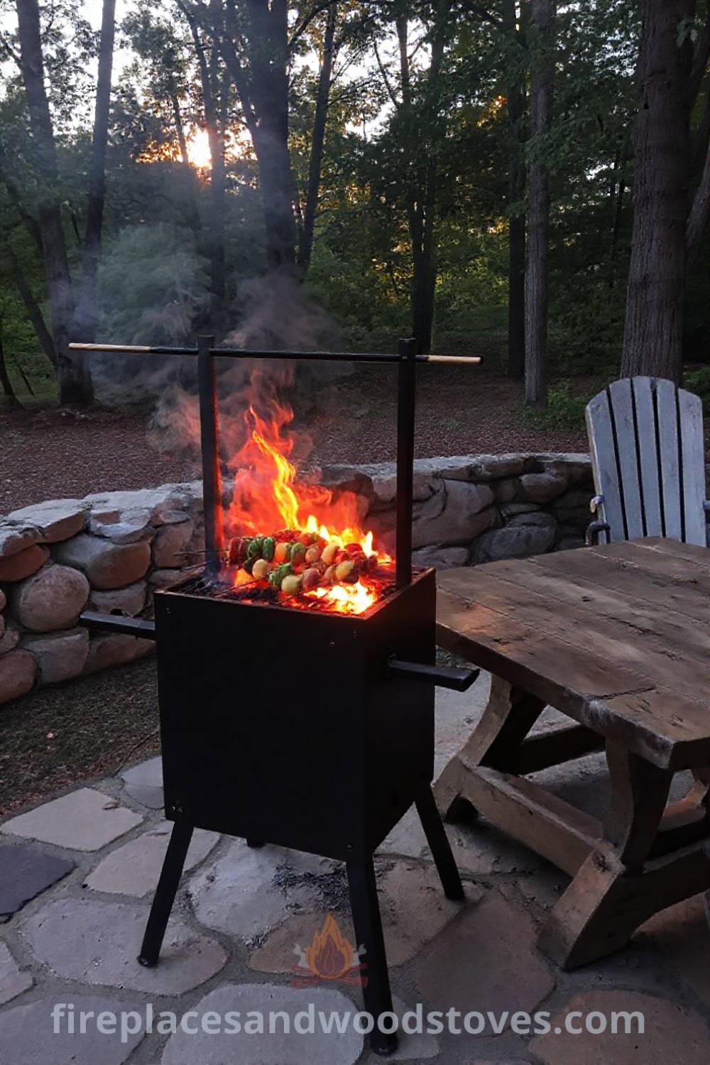 Spit BBQ on a stone patio surrounded by trees, with skewered vegetables and marinated meats cooking over flames, creating a cozy atmosphere for gatherings and outdoor enjoyment. Visit patioandhomefurniture.com for incredible ideas that will transform your backyard.