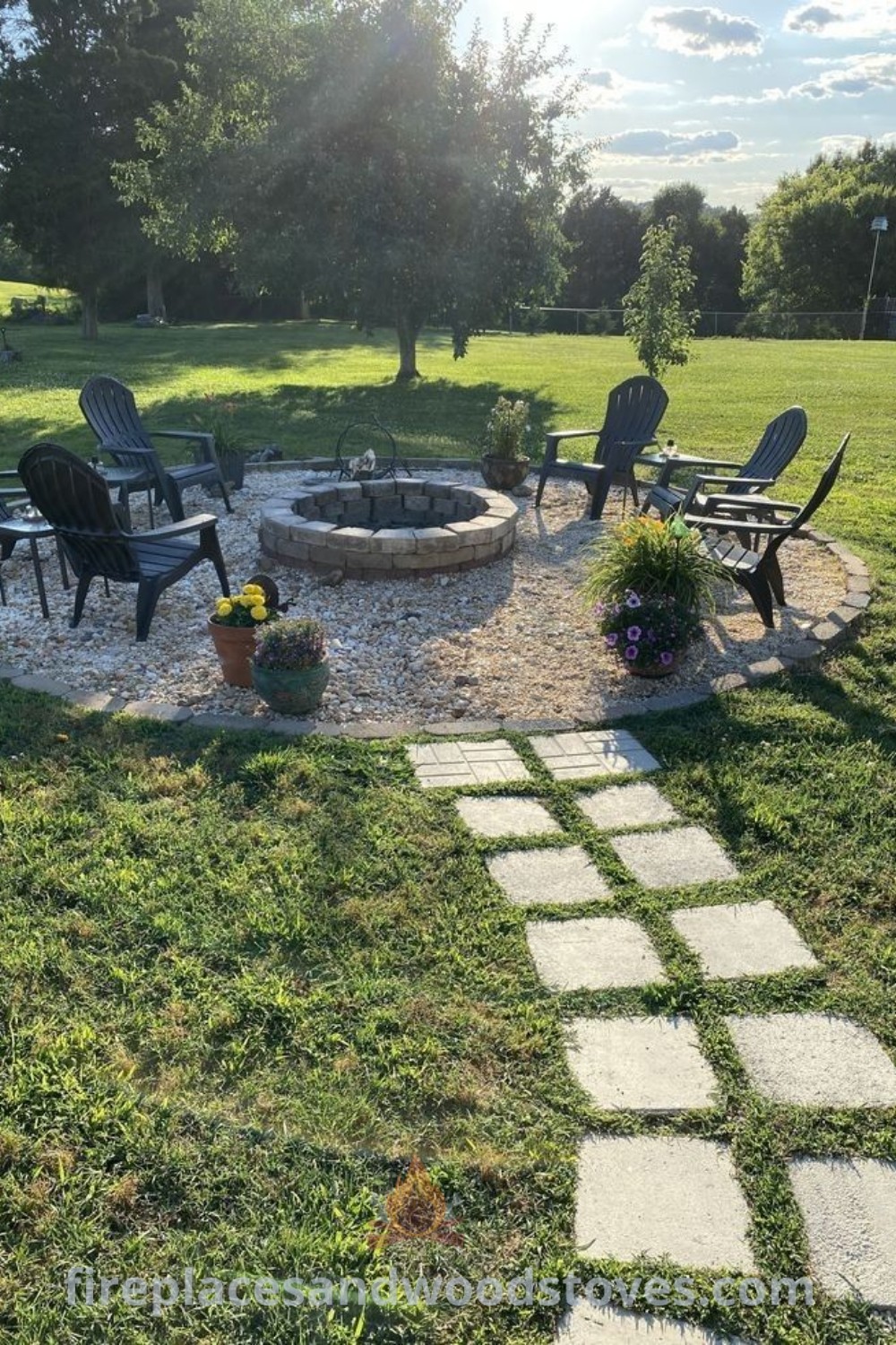 A fire pit area surrounded by lawn chairs, featuring a grass and flower landscape, complemented by creative pathway ideas like gravel and stepping stones. Transform your backyard into a cozy retreat with stylish designs from patioandhomefurniture.com.