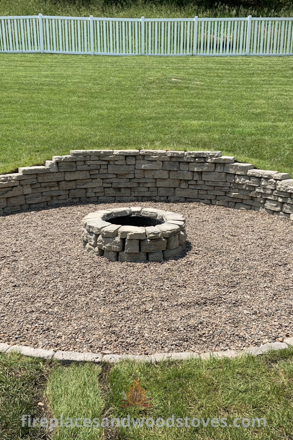 A cozy outdoor fire pit surrounded by gravel and grass in a sloped backyard, perfect for enhancing outdoor living spaces. Discover stylish fire pit ideas that transform your yard, featured on patioandhomefurniture.com.