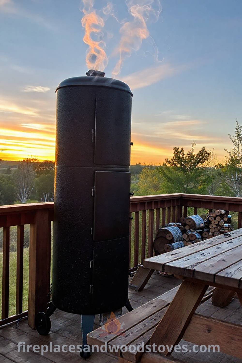 Towering vertical smoker barbecue on a wooden deck with a weathered picnic table and sauces nearby, complementing a cozy outdoor atmosphere. Visit patioandhomefurniture.com for ideas that will wow your guests with stylish designs transforming your backyard.