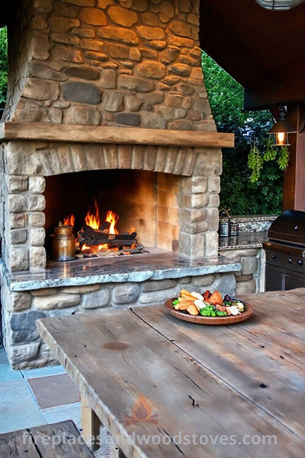 Outdoor kitchen with a wood-burning fireplace, weathered stone, granite countertops, and hanging herbs, setting a cozy atmosphere for gatherings, ideal for creating unforgettable memories. Visit patioandhomefurniture.com for incredible ideas that will wow your guests.