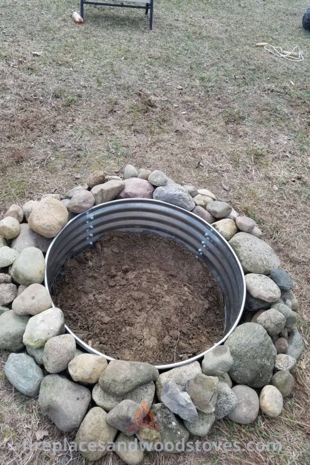 A rustic fire pit made of river rocks in a scenic field, complete with a bench behind it, creating a stylish outdoor space. Perfect for cozy gatherings and cooking, this setup showcases incredible ideas for transforming your backyard. Explore more designs at patioandhomefurniture.com.