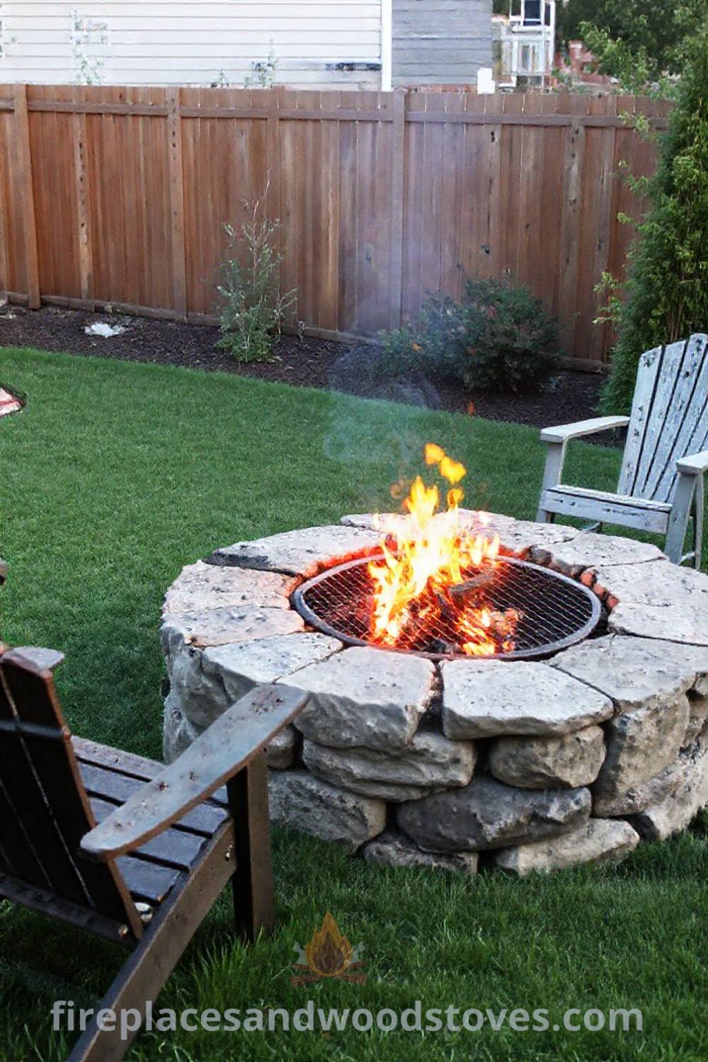 Stone charcoal fire pit with built-in grill in a cozy backyard setting surrounded by weathered chairs, creating an inviting outdoor atmosphere perfect for gatherings. Visit patioandhomefurniture.com for stylish ideas that will wow your guests.