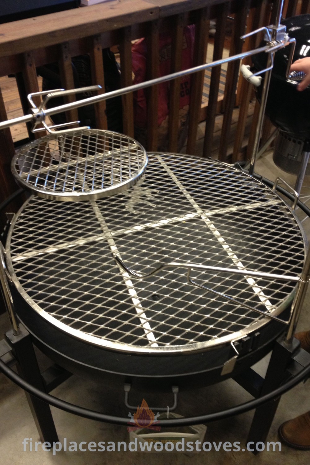 Two round grills on a metal stand next to a wooden table, ideal for outdoor cooking and cozy gatherings. Discover incredible outdoor firepit ideas at patioandhomefurniture.com.