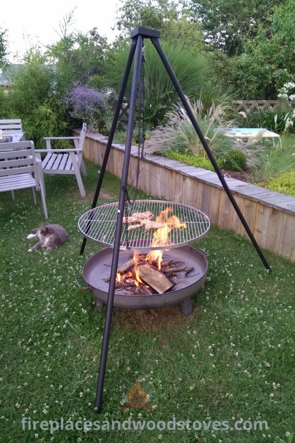 A cozy backyard fire pit with chairs around it and a cat laying on the grass, showcasing creative designs that transform the yard into an inviting space. Discover stylish fire pit ideas at patioandhomefurniture.com.