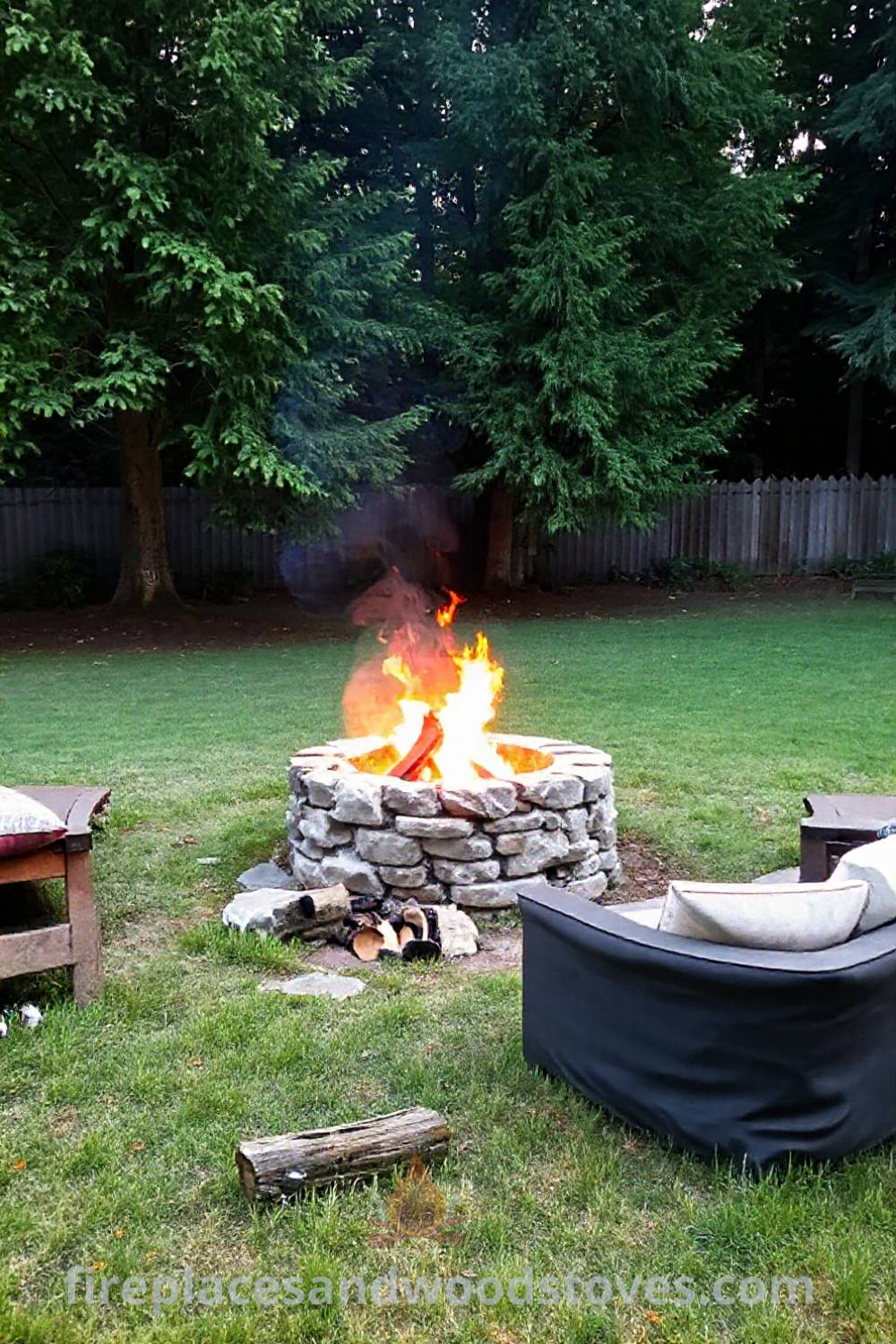 Stone fire pit in a grassy backyard surrounded by mismatched seating, creating a cozy atmosphere for gatherings and evenings under the stars, featuring warm light, scattered logs, and cushions. Visit patioandhomefurniture.com for stylish outdoor designs transforming your backyard.