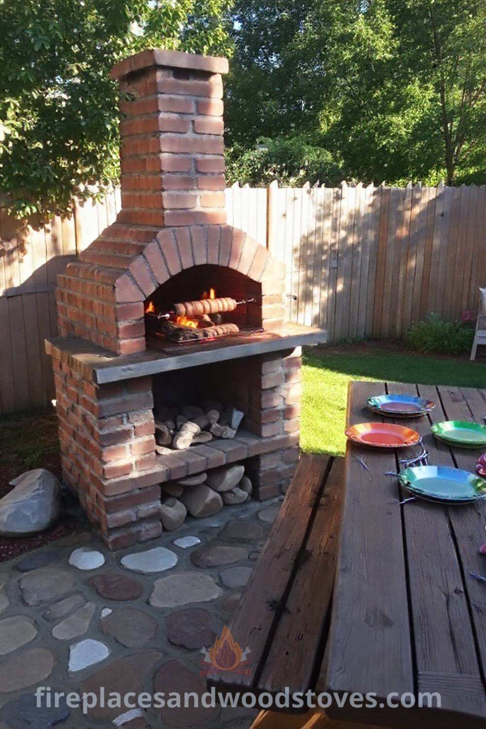 Sturdy brick barbecue with a rotisserie in a sun-drenched backyard, surrounded by a wooden picnic table set with colorful plates, inviting warm gatherings. Visit patioandhomefurniture.com for stylish ideas transforming your backyard into a cozy outdoor dining area.