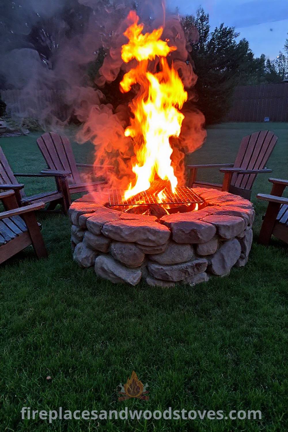 Traditional stone fire pit with a wood-fueled grill in a grassy yard, surrounded by wooden chairs, creating a cozy atmosphere for gatherings with friends and family. Visit patioandhomefurniture.com for stylish outdoor design inspiration.