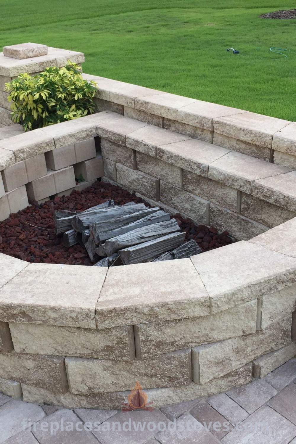 A round brick fire pit surrounded by curved seating and planters, creating a cozy outdoor atmosphere for gatherings. Explore stylish outdoor designs that transform your backyard at patioandhomefurniture.com.