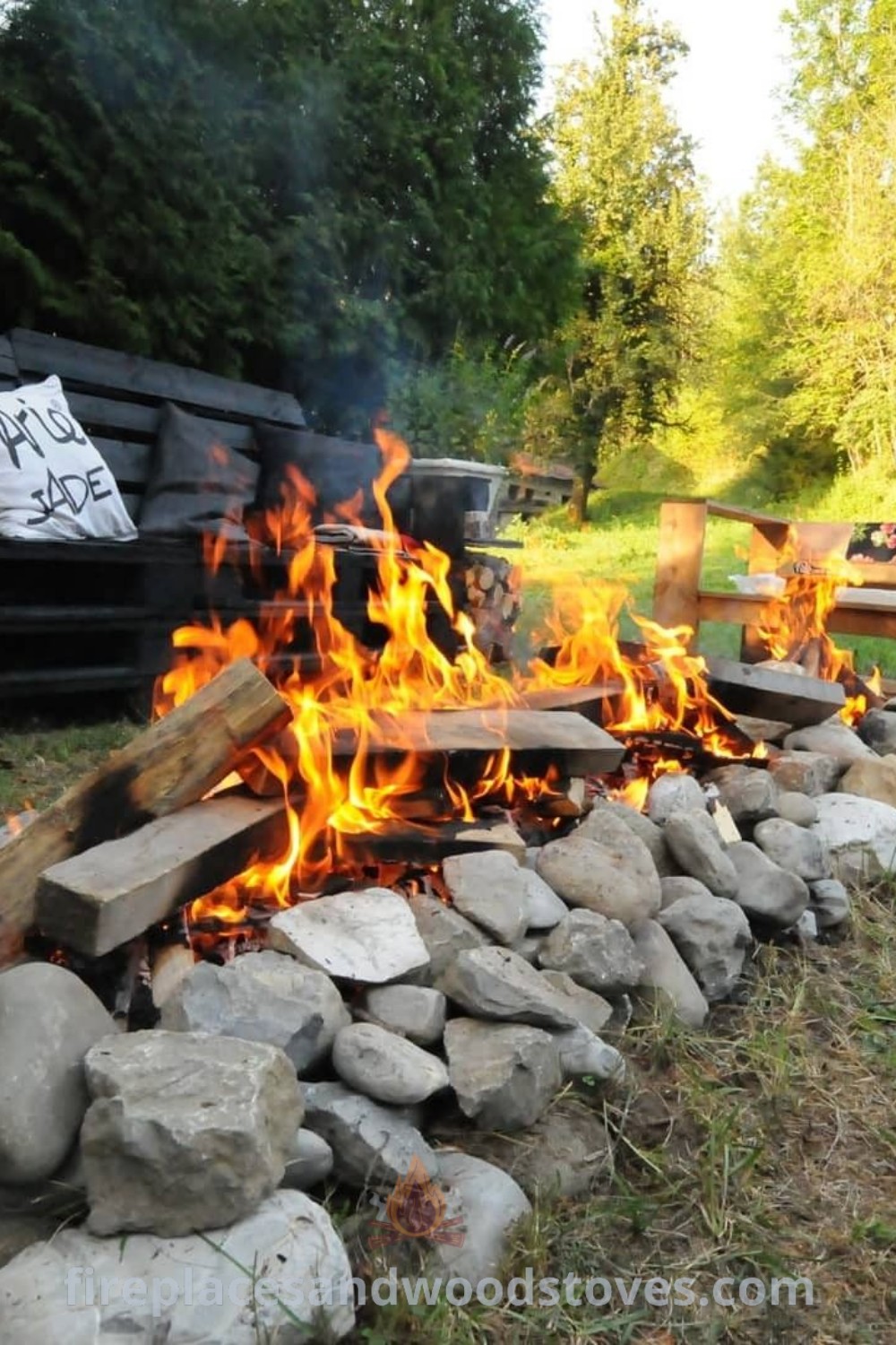 A romantic fire pit with rocks and logs in a wooded garden, showcasing stylish designs that transform your outdoor space into a cozy retreat. Explore incredible fire pit ideas at patioandhomefurniture.com.