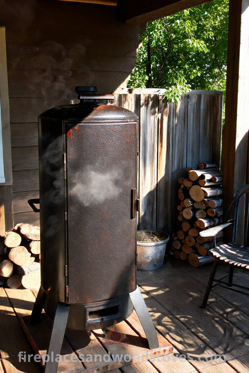 Vertical smoker barbecue on a wooden patio with sun-dappled surroundings, mismatched chairs, and seasoned wood logs leaning against a weathered fence, creating a cozy outdoor space perfect for gatherings. Visit patioandhomefurniture.com for stylish outdoor design ideas you