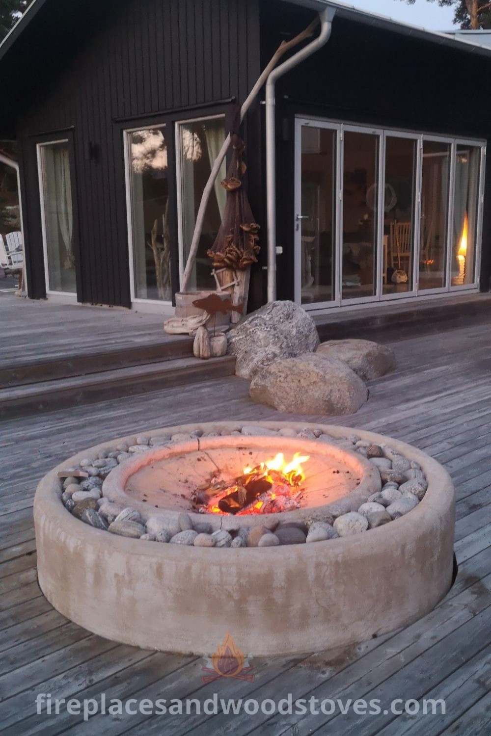 A cozy fire pit on a wooden deck beside a building with windows, featuring stylish boma ideas and fire pots, perfect for an inviting patio area. Discover outdoor inspiration at patioandhomefurniture.com.