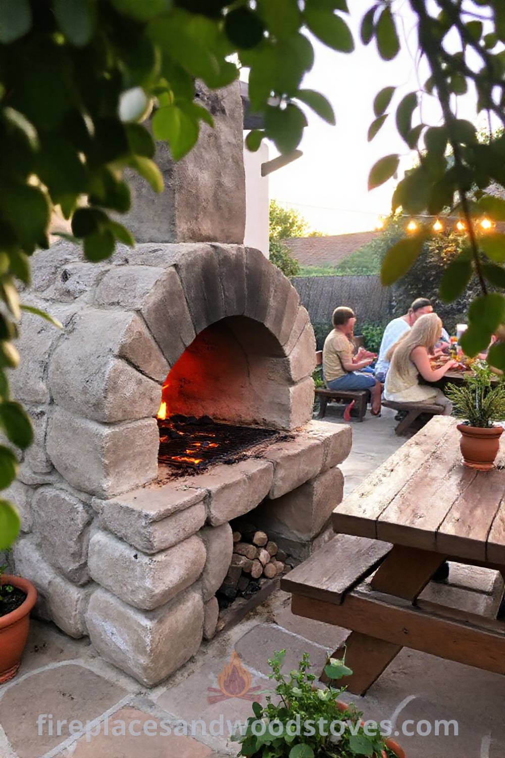 Stone BBQ oven on a charming patio surrounded by friends, a wooden picnic table, and green plants in terracotta pots, creating a cozy outdoor atmosphere perfect for gatherings. Visit patioandhomefurniture.com for incredible ideas that will wow your guests.