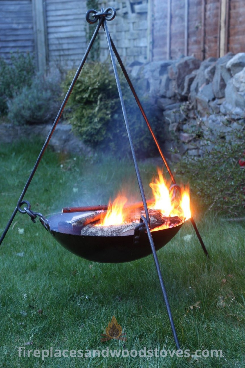 A fire pit in the center of a yard, surrounded by a cozy outdoor atmosphere, featuring two sticks. This stylish addition offers incredible ideas for cozy gatherings and outdoor events. Explore more designs for your backyard at patioandhomefurniture.com.