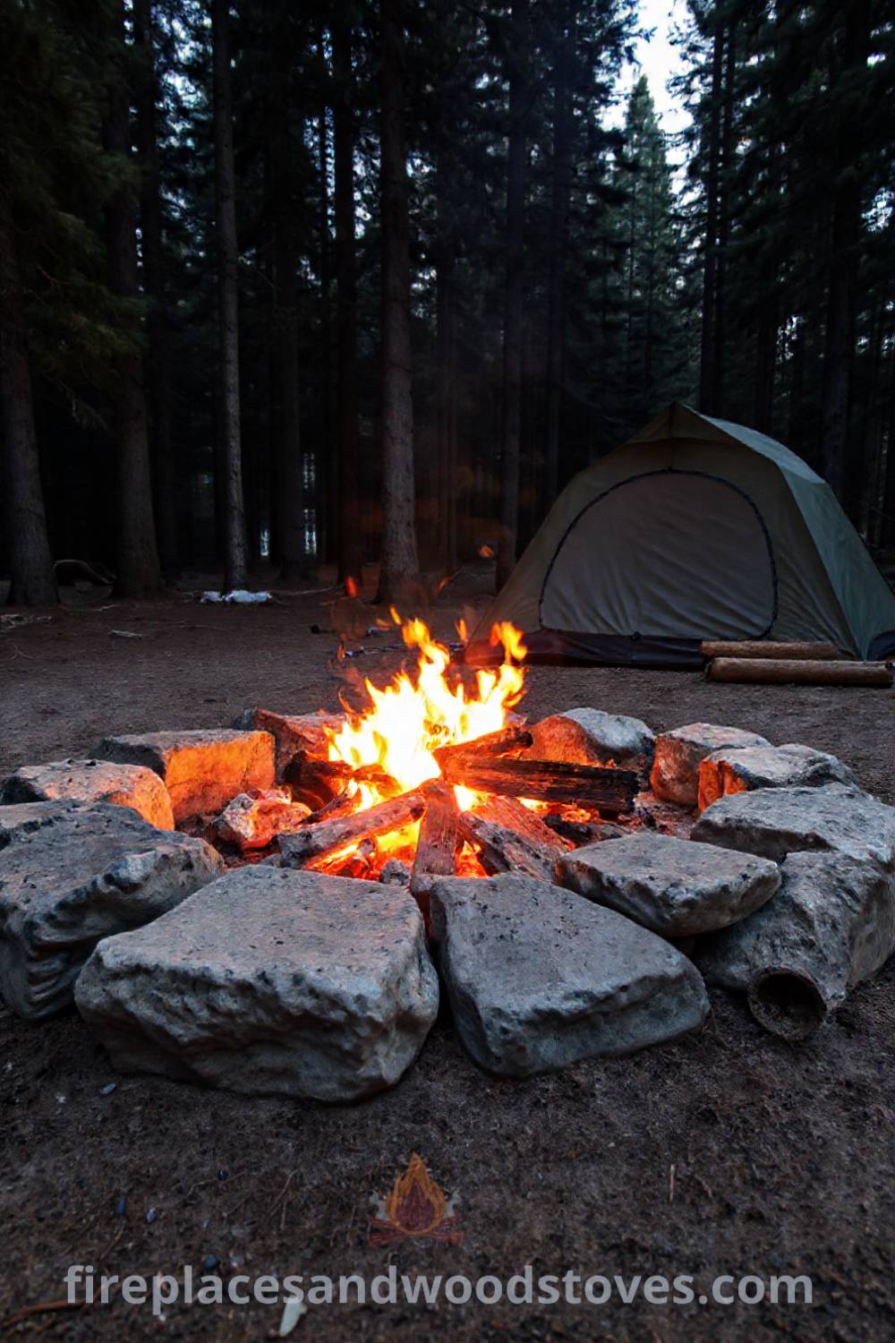 Camping fire pit nestled in a clearing with weathered stones, towering pines, and a tent nearby, creating a cozy outdoor ambiance perfect for gatherings. Visit patioandhomefurniture.com for stylish ideas that will wow your guests.