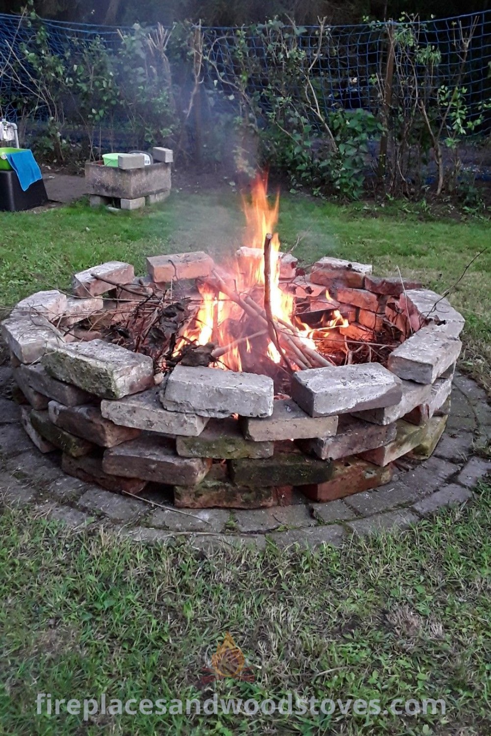 A fire pit in the middle of grass, designed with rocks, creating a stylish campfire area perfect for gatherings and outdoor decor inspiration. Discover more cozy outdoor ideas at patioandhomefurniture.com.