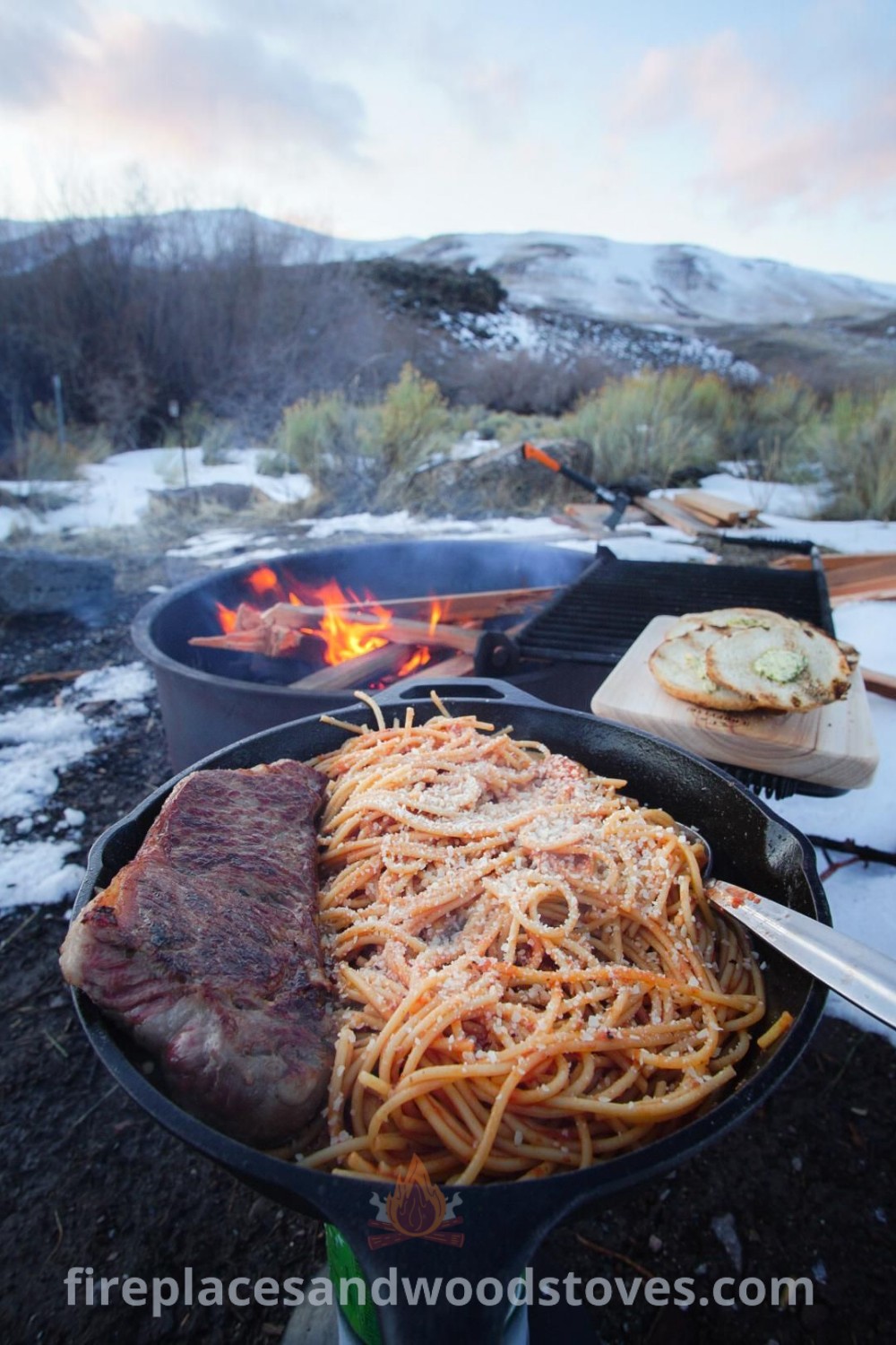 Food being cooked on an outdoor grill in the snow with mountains in the background, showcasing delicious winter camping food ideas like steak and easy camping meals. Perfect inspiration for outdoor recipes and fire food, discover more at patioandhomefurniture.com.