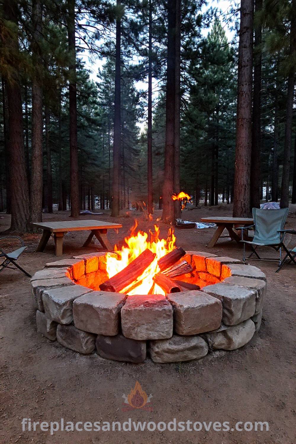 Rustic stone camping fire pit nestled among tall pines with glowing firewood, surrounded by wooden tables and camping chairs, creating a cozy outdoor ambiance perfect for memorable gatherings. Visit patioandhomefurniture.com for stylish outdoor ideas that will wow your guests.