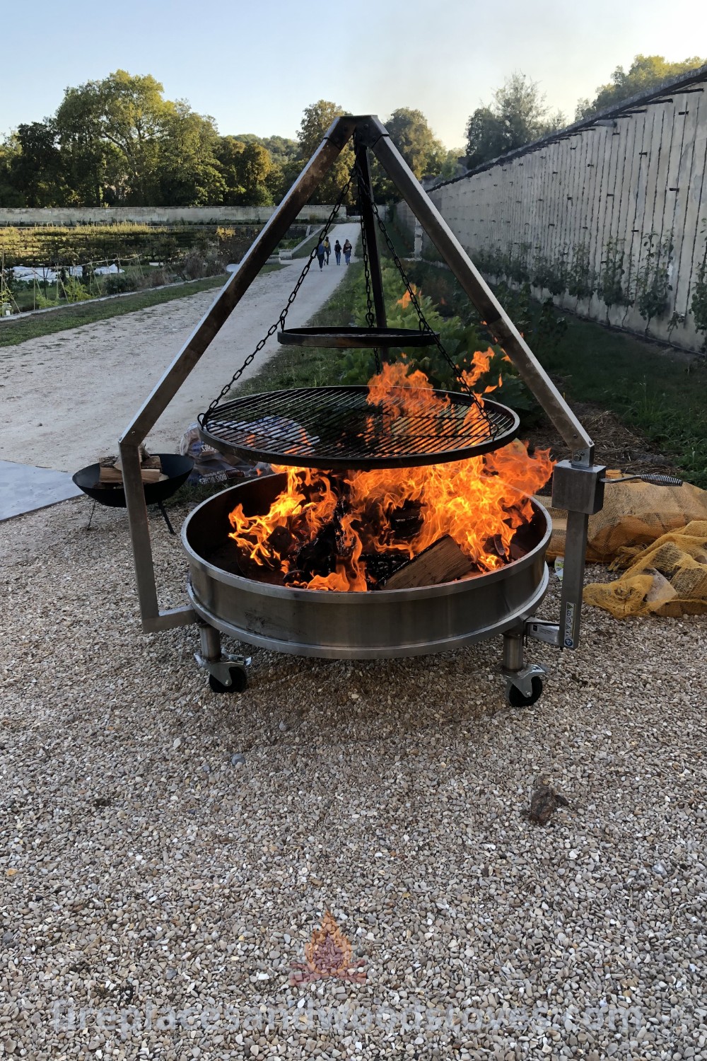 A contemporary fire pit BBQ on a gravel field, surrounded by warm stones, perfect for outdoor gatherings and cooking. Discover stylish outdoor ideas that transform your backyard at patioandhomefurniture.com.