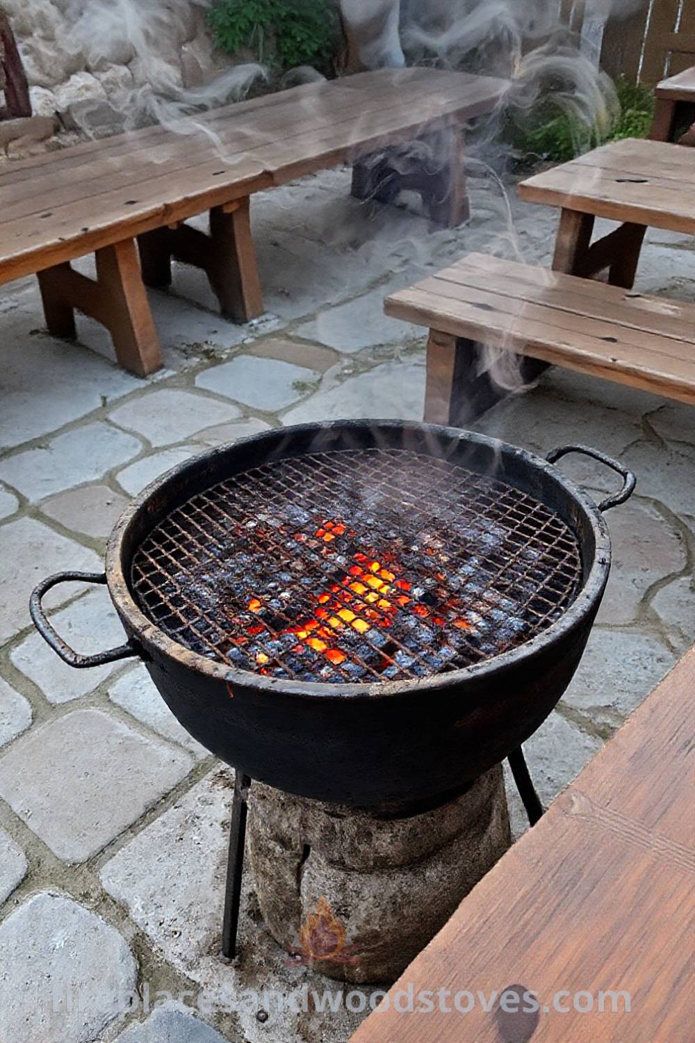 Traditional Turkish mangal barbecue on a stone patio with glowing charcoal embers, surrounded by wooden benches, creating a cozy outdoor gathering space ideal for feasts with family and friends. Visit patioandhomefurniture.com for incredible outdoor design inspiration.