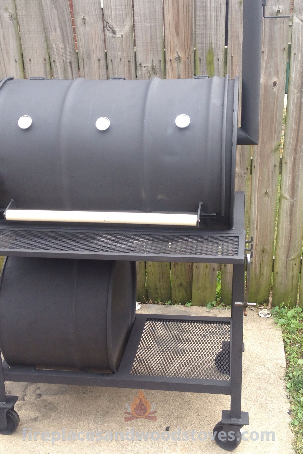 An outdoor BBQ grill sitting on top of a sidewalk next to a wooden fence, showcasing a smoker BBQ that enhances any outdoor gathering. Elevate your backyard with stylish BBQ grill ideas that inspire creativity and functionality. Discover more outdoor inspiration at patioandhomefurniture.com.