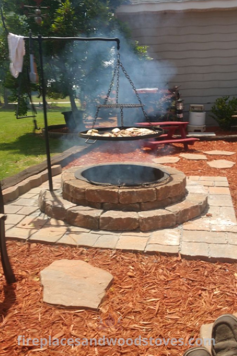 A person enjoying a cozy evening by a brick fire pit in a beautifully decorated garden, showcasing stylish outdoor decor and inviting ambiance. Discover creative outdoor ideas for your home at patioandhomefurniture.com.